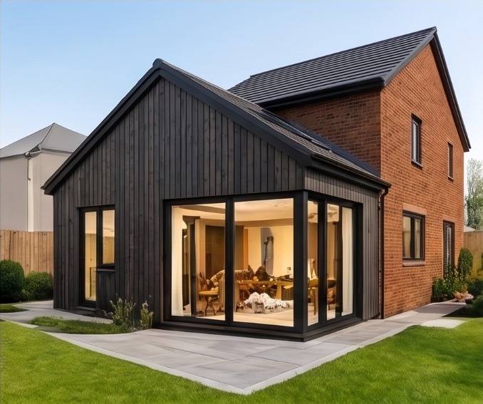Black timber-clad gabled extension with large glazed openings to a modern brick home
